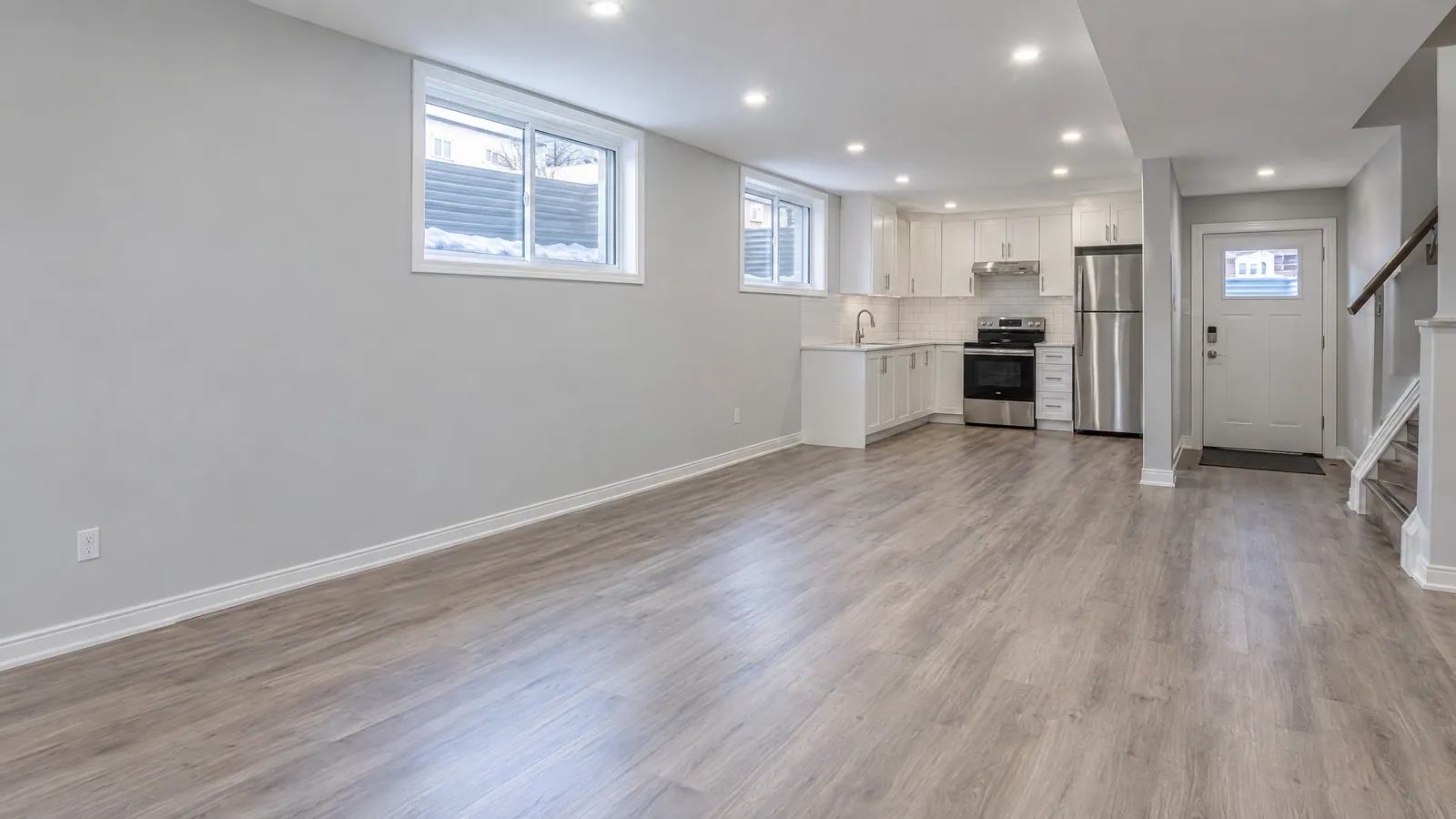 Empty, freshly painted basement apartment with two high sliding windows and its own entrance door